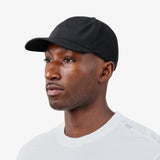 Model wearing black performance baseball cap with perforated side panels, three-quarter profile