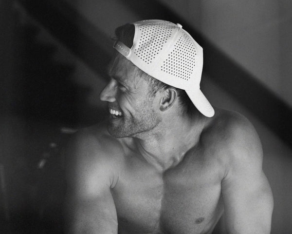 Smiling shirtless man in side profile wearing a white perforated backward baseball cap (black-and-white photo) - Daily Tech Hat Grey