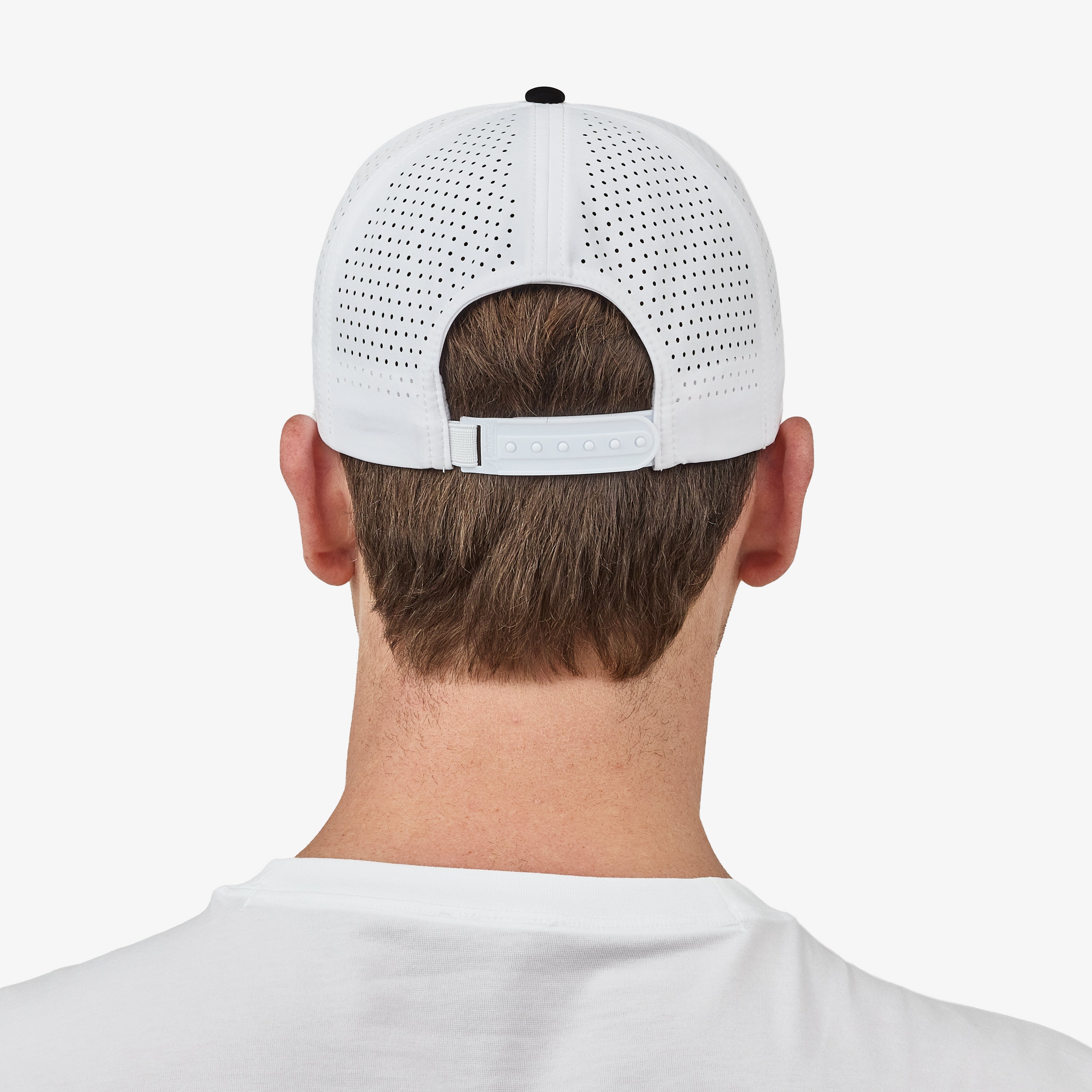 Back view of a man wearing a white perforated baseball cap with an adjustable strap, shown against a light gray studio background.