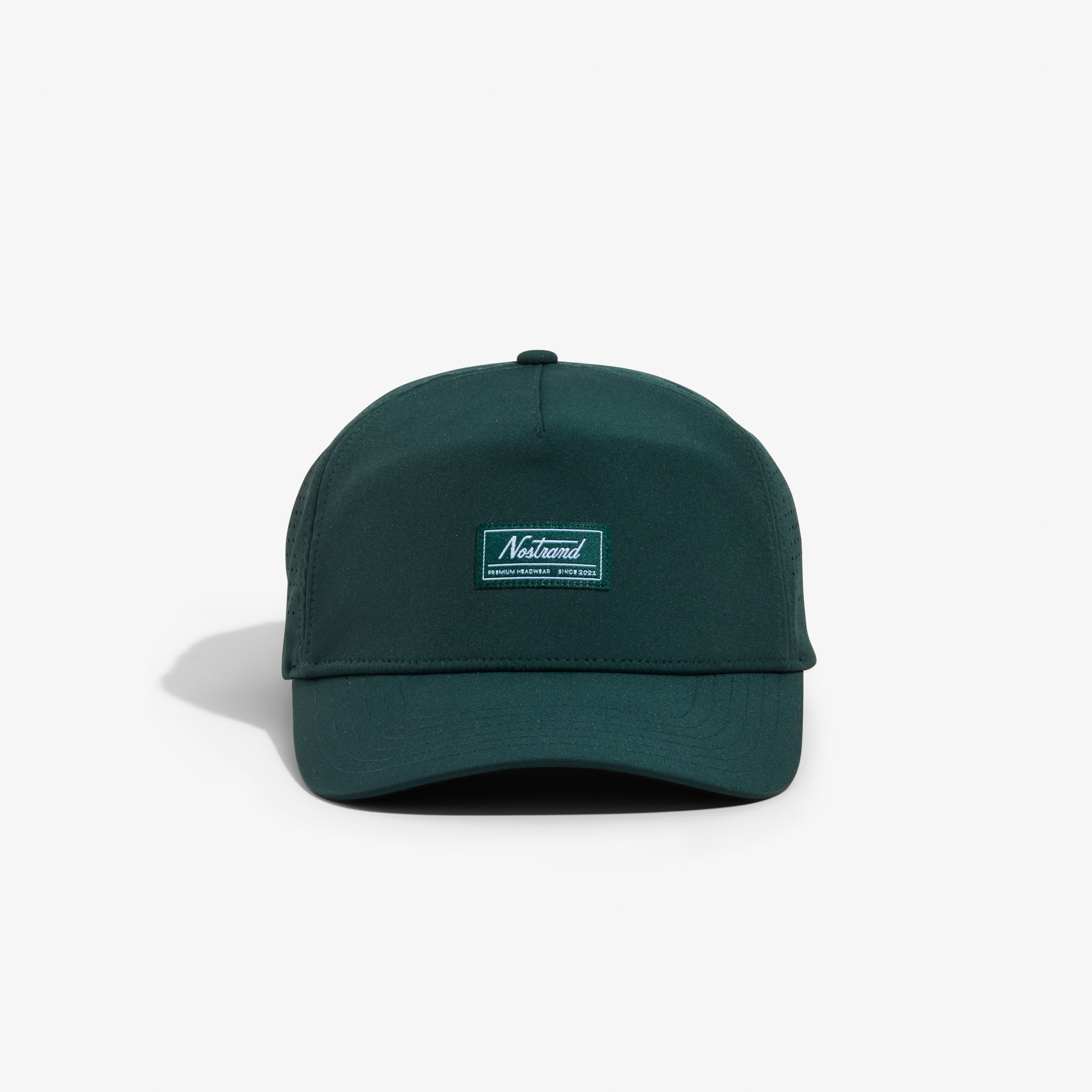 Dark cypress-green performance cap with stitched label reading: Nostrand PREMIUM HEADWEAR SINCE 2021.