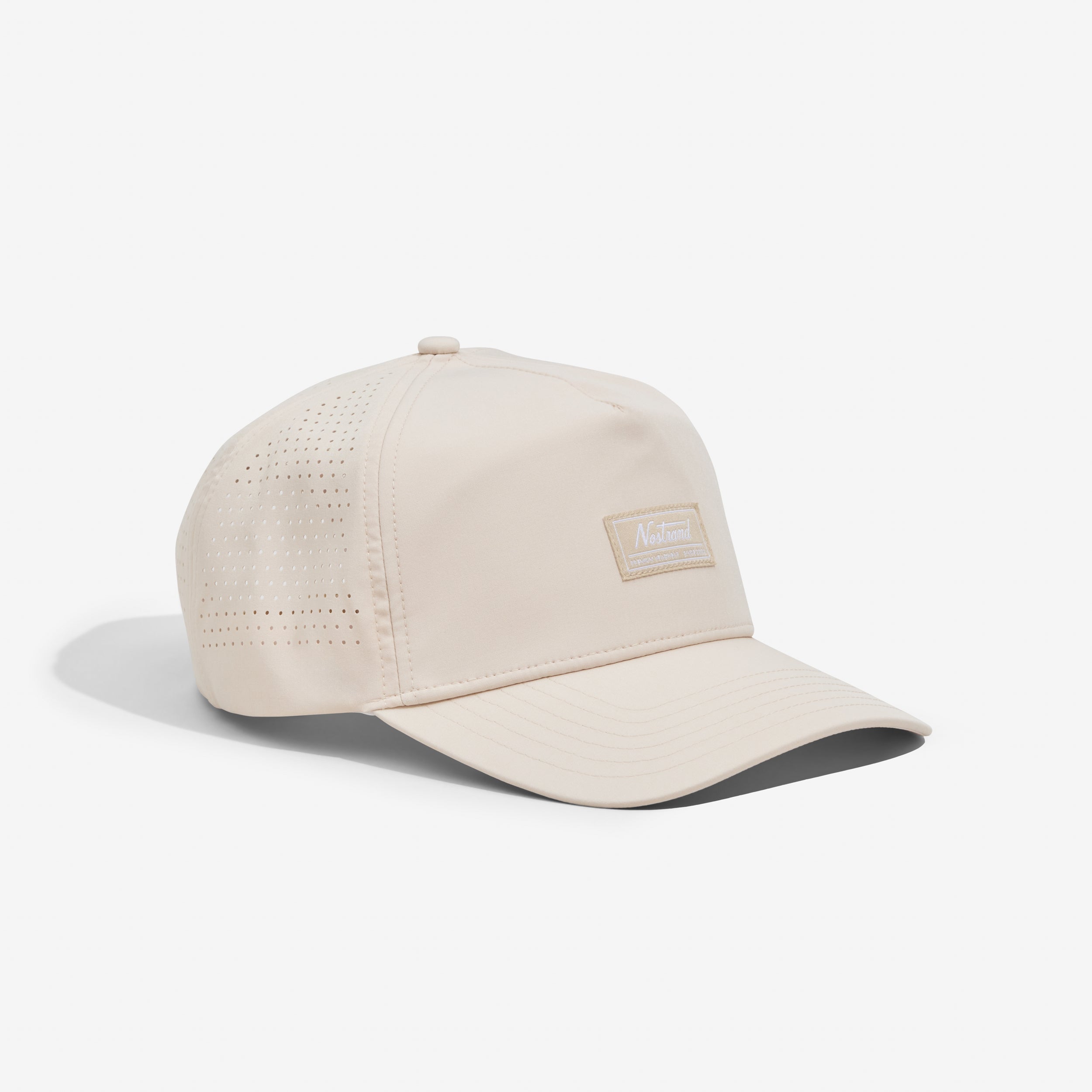 Beige perforated six-panel baseball cap with curved brim and rectangular "Natural" patch on the front