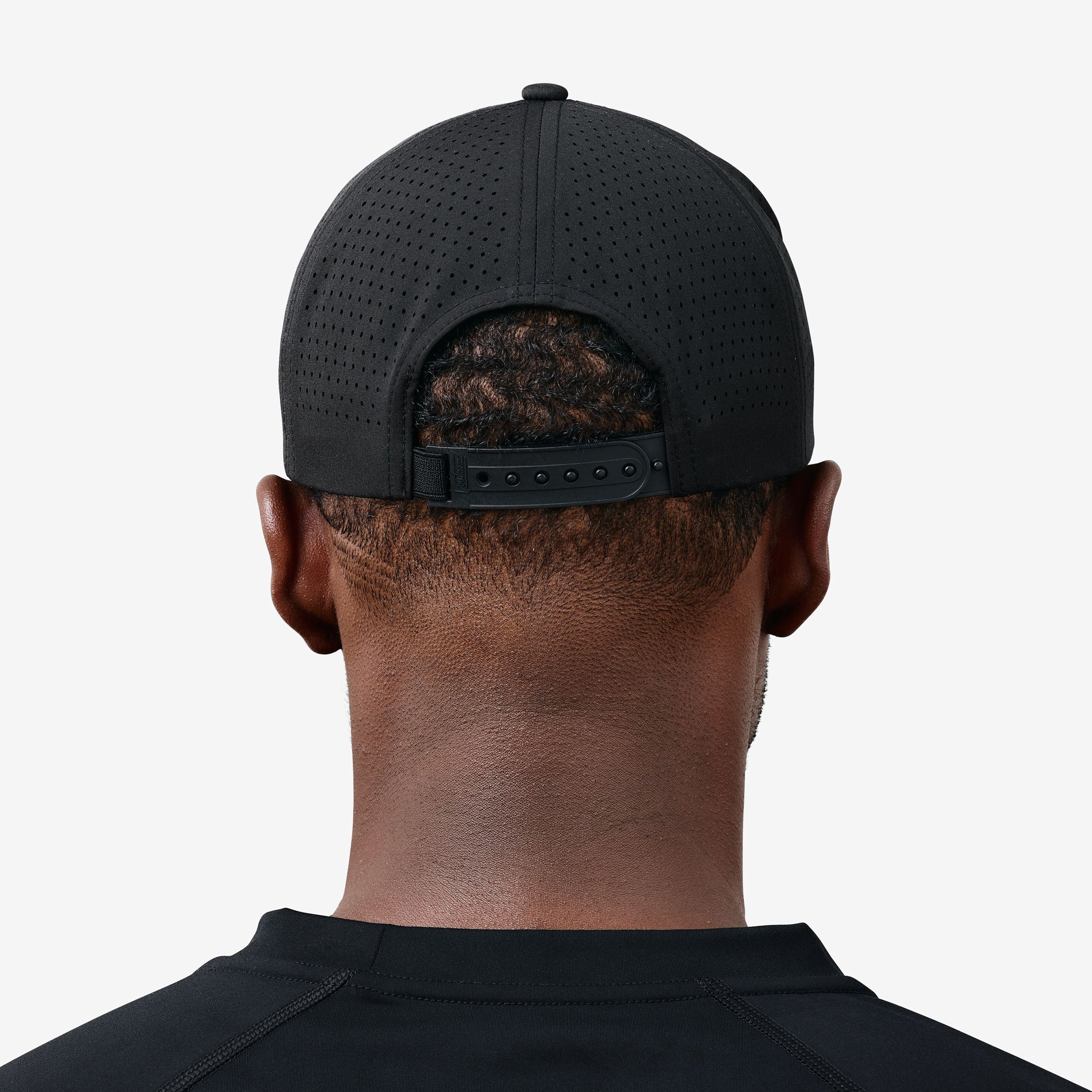 Rear view of person wearing black Daily Tech Hat 3 showing perforated back panels and adjustable strap.